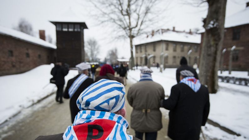 Sobrevivientes pasan por delante de una torre de vigilancia después de rendir homenaje a los caídos en el lugar de ejecución del "muro de la muerte" en el antiguo campo de concentración de Auschwitz en Oswiecim (Polonia), en el 70º aniversario de la liberación del campo de muerte nazi el 27 de enero de 2015. (ODD ANDERSEN/AFP/Getty Images)

