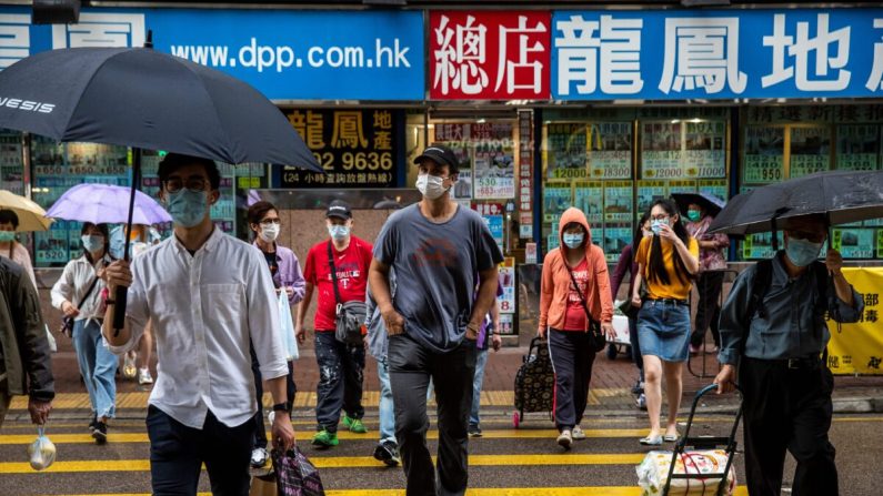 El fundador y CEO de ImpactHK, Jeff Rotmeyer (C), cruza una calle después de repartir suministros de mascarillas faciales, desinfectantes de manos, alimentos y bebidas a los desamparados y personas necesitadas en Hong Kong el 28 de marzo de 2020. (Isaac Lawrence/AFP vía Getty Images)