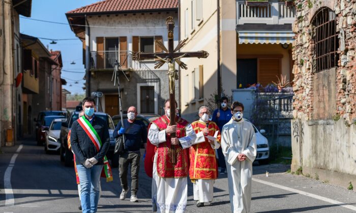 El párroco de la iglesia de Santa Maria Assunta en Pontoglio, Don Giovanni Cominardi (centro), es escoltado por el alcalde de Pontoglio, Alessandro Seghezzi (izq.), durante una procesión del Vía Crucis como parte de las celebraciones del Viernes Santo en Pontoglio, Italia, el 10 de abril de 2020. (Miguel Medina /AFP vía Getty Images)