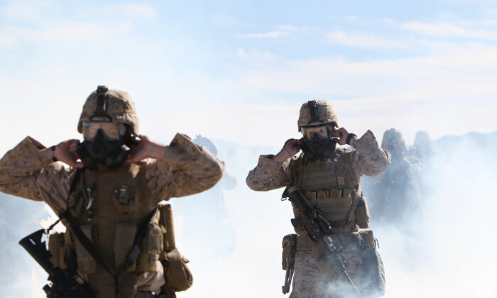 Marines y marineros de la Compañía E, 2º Batallón, 7º Regimiento de Marines, rompen los sellos de sus mascarillas de gas M50 en una nube de gas CS durante un ejercicio de gas al aire libre realizado en el rango 210 el 26 de enero de 2011. (Lance Cpl. Andrew Thorburn/DoD)