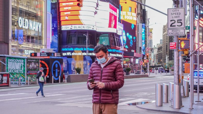 Un hombre con una máscara facial médica está usando su teléfono en Times Square, Nueva York, el 4 de abril de 2020. (Chung I Ho / The Epoch Times)
