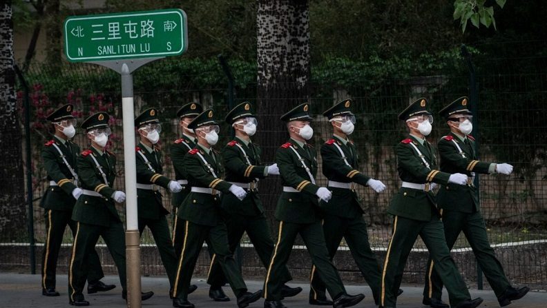 Los oficiales de policía chinos llevan mascarillas de protección mientras marchan durante un cambio de turno el 14 de abril de 2020 en Beijing. (Kevin Frayer/Getty Images)
