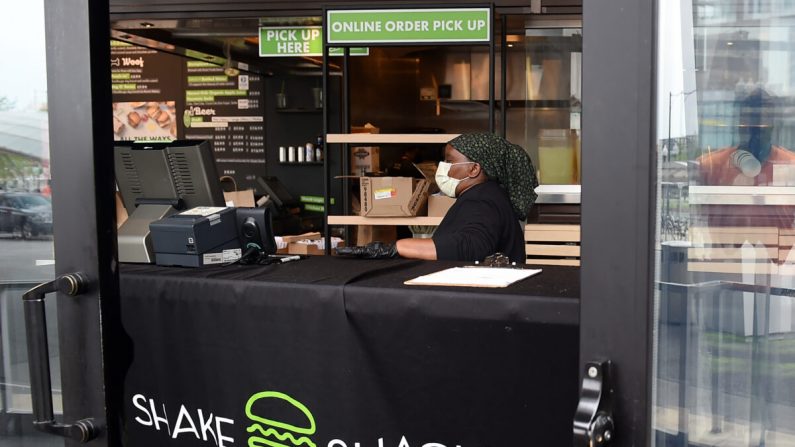 Una empleada de Shake Shack usa mascarilla mientras prepara pedidos de comida para su entrega durante la pandemia de Coronavirus en Arlington, Virginia, el 20 de abril de 2020. (OLIVIER DOULIERY/AFP a través de Getty Images)