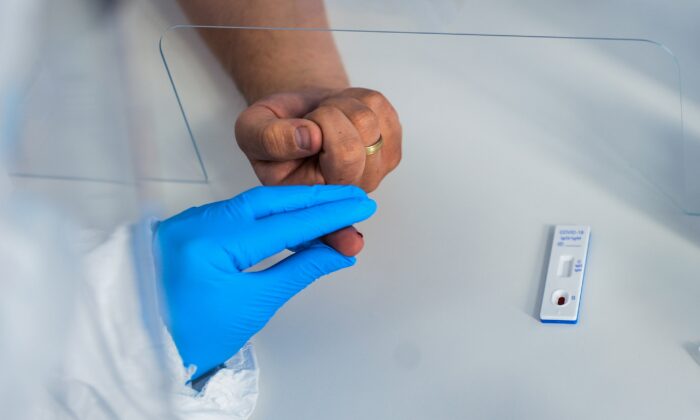 Una trabajadora del área de salud usa una máscara protectora y un traje mientras extrae la sangre de un paciente para realizar una prueba de anticuerpos del COVID-19 en el Hospital Dworska de Cracovia, Polonia, el 9 de abril de 2020. (Omar Marques/Getty Images)