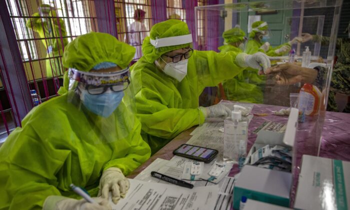 Personal médico examina a las personas para detectar COVID-19 utilizando kits de prueba rápida de anticuerpos, en una escuela convertida en un centro de pruebas masivas, en Manila, Filipinas, el 24 de abril de 2020. (Ezra Acayan / Getty Images)