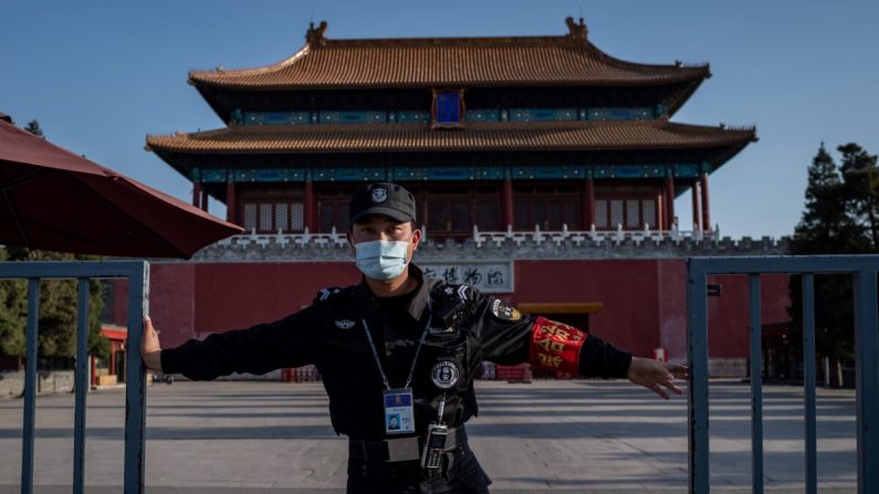 Un guardia de seguridad con mascarilla facial en medio de las preocupaciones sobre el virus del PCCh cierra una puerta fuera de la ciudad prohibida en Beijing el 12 de abril de 2020. (Nicolas Asfouri/AFP a través de Getty Images)