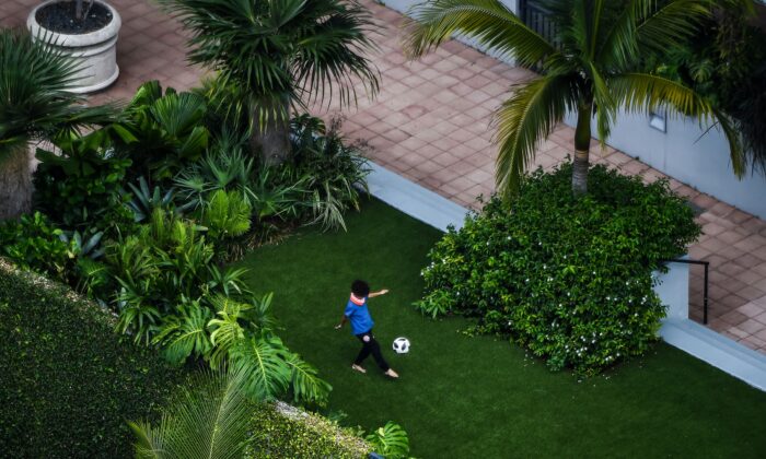 Un niño juega fútbol solo en un jardín en medio de temores sobre la propagación del virus CCP en Miami, Florida, el 6 de abril de 2020. (Chandan Khanna / AFP a través de Getty Images)