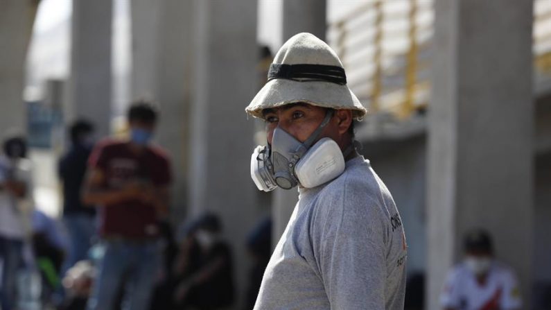 Cientos de personas descansan a un lado de la autopista Panamericana Sur en Lima, en su recorrido a pie hacia el departamento de Apurimac. EFE/Paolo Aguilar
