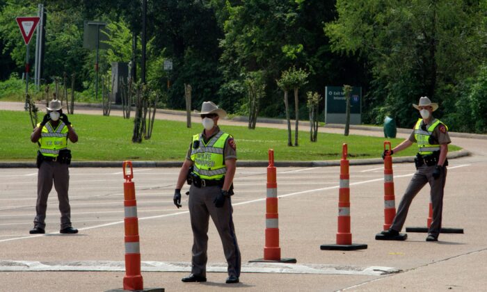 Fuerzas de seguridad de Texas esperan a que los conductores lleguen a un punto de control, en la frontera entre Louisiana y Texas, en Orange, Texas, el 7 de abril de 2020. (Mark Felix/AFP a través de Getty Images)