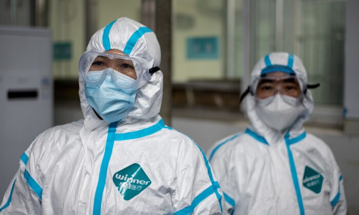 Trabajadores médicos que llevan trajes de protección contra materiales peligrosos como medida preventiva contra el coronavirus COVID-19 son atendidos en la clínica de la fiebre del Hospital Huanggang Zhongxin en Huanggang, en la provincia central de Hubei de China, el 26 de marzo de 2020. (Noel Celis/AFP vía Getty Images)