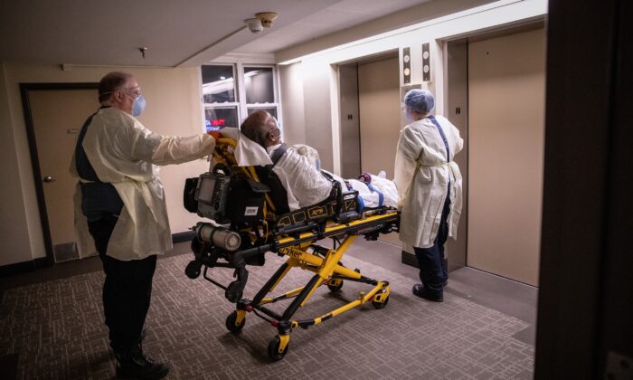 Médicos con equipo de protección personal, transportan un paciente con síntomas de COVID-19 de su departamento en Stamford, Connecticut el 4 de abril de 2020. (John Moore/Getty Images)