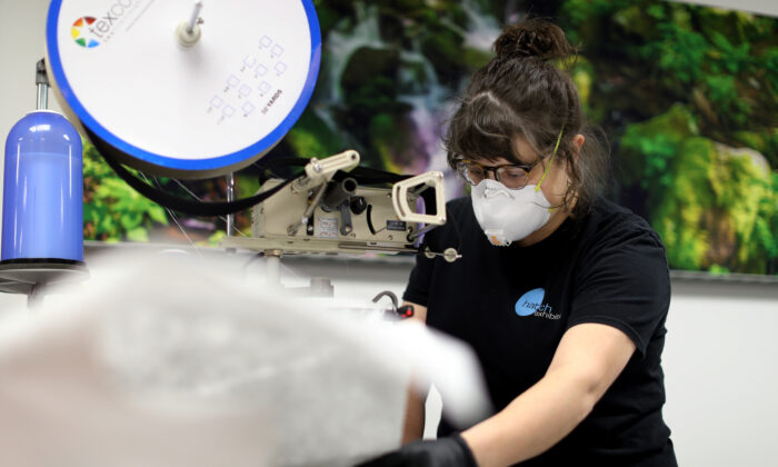 El fabricante e instalador de Hatch Exhibits Morgan Frailey cose batas médicas que la compañía produce para proteger a la gente del virus del PCCh, en Elkridge, Maryland, el 31 de marzo de 2020. (Chip Somodevilla/Getty Images)
