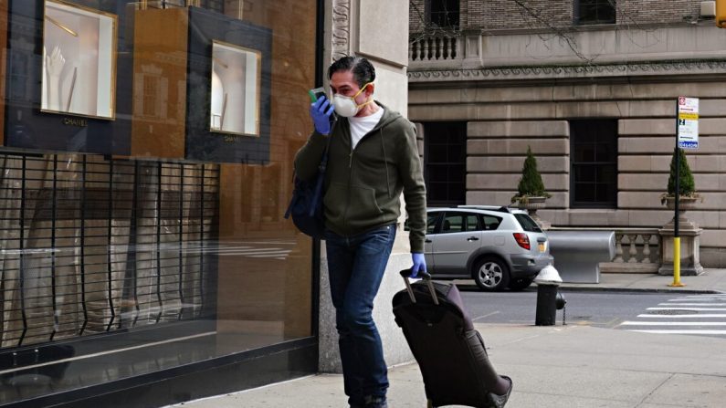 Un hombre que llevaba una máscara protectora y guantes habla por teléfono celular en una bolsa ziplock durante la pandemia COVID-19 en la ciudad de Nueva York el 8 de abril de 2020. (Cindy Ord/Getty Images)