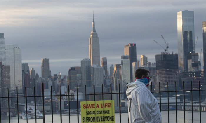 Un hombre se cubre la cara mientras el sol se levanta detrás en Manhattan visto desde Weehawken, New Jersey el 6 de abril de 2020. (Kena Betancur/Getty Images)