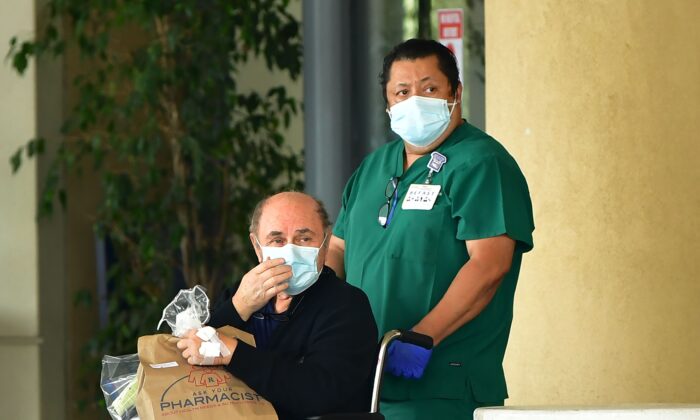 Un trabajador médico con una máscara empuja a un hombre en silla de ruedas en Burbank, California, el 7 de abril de 2020, en medio de la pandemia del virus del PCCh que afecta también a Estados Unidos. (Frederic J. Brown/AFP vía Getty Images)