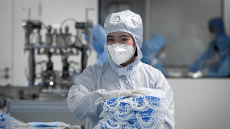 Una trabajadora que usa un traje protector tiene máscaras para empacar en Naton Medical Group, una compañía que fabrica equipos médicos en Beijing, el 24 de abril de 2020. (Wang Zhao/AFP a través de Getty Images)