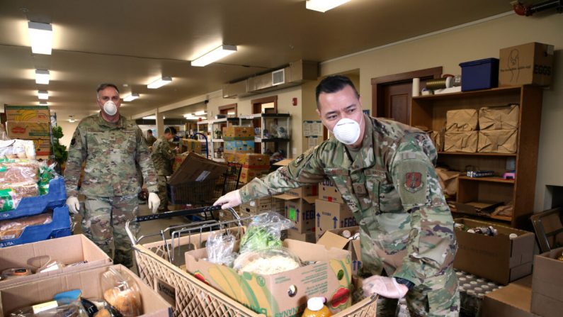 El jefe Allan Lawson (D) y el Coronel Gent Welsh, ambos de la Guardia Nacional Aérea de Washington, ayudan a distribuir alimentos con voluntarios en el banco de alimentos del Condado de Nourish Pierce establecido en la Iglesia Luterana de Mountain View en Edgewood, Washington, el 4 de abril de 2020. (Karen Ducey/Getty Images)