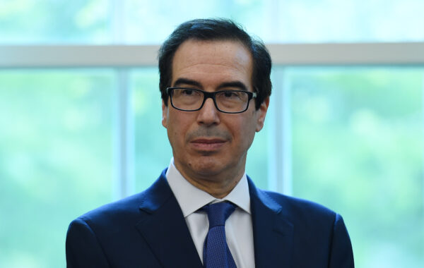 El secretario del Tesoro de EE.UU. Steven Mnuchin mira mientras el presidente Donald Trump firma el Programa de Protección de Cheques y la Ley de Mejora de la Atención Médica en el Despacho Oval de la Casa Blanca en Washington el 24 de abril de 2020. (Olivier Douliery/AFP vía Getty Images)