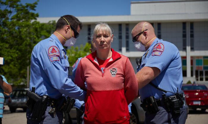 Una manifestante de una organización denominada ReopenNC es arrestada después de negarse a abandonar un estacionamiento durante una manifestación en contra el bloqueo del virus del PCCh de Carolina del Norte en el Estado de Carolina del Norte en Raleigh, Carolina del Norte, el 14 de abril de 2020. (Logan Cyrus / AFP a través de Getty Images)