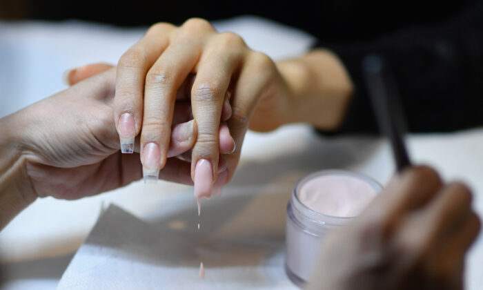 La bloguera de belleza colombiana Paula Galindo se hace la manicura con la artista de uñas y empresaria Jenny Bui, alias "La Reina del Bling", en su salón de uñas en el distrito del Bronx de la ciudad de Nueva York el 10 de enero de 2020 (Angela Weiss/AFP vía Getty Images)