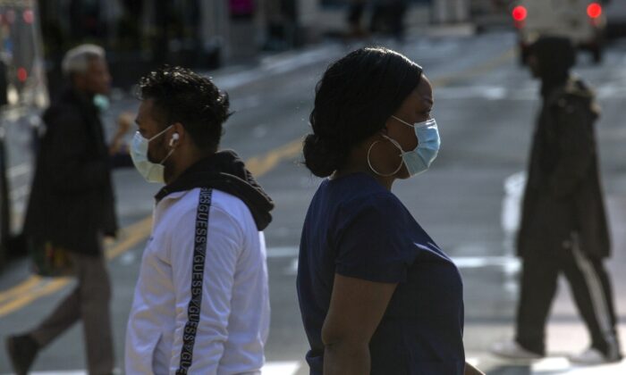 La gente usa mascarillas cuando camina por la calle 34 en la ciudad de Nueva York el 6 de abril de 2020. (Kena Betancur/Getty Images)