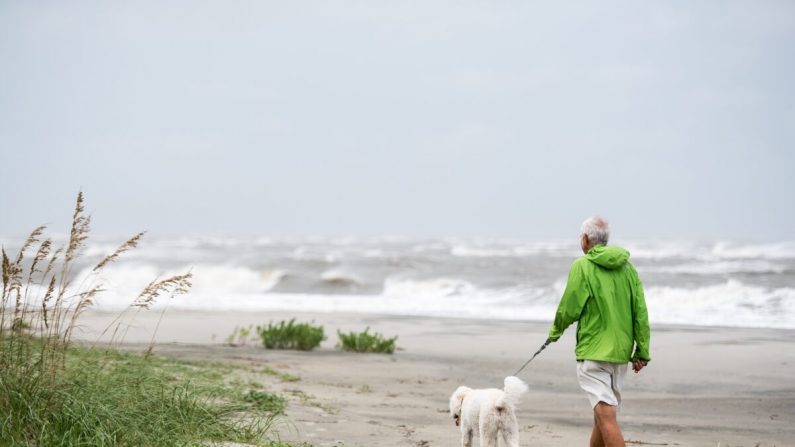 Un hombre pasea a su perro en la playa de la isla de Sullivan, Carolina del Sur, el 4 de septiembre de 2019. (Sean Rayford/Getty Images)