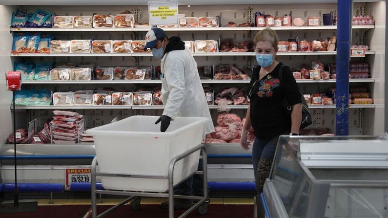 Wilson Castro lleva una máscara y guantes mientras repone las estanterías del departamento de carnes del supermercado Presidente el 13 de abril de 2020 en Miami, Florida. (Joe Raedle/Getty Images)