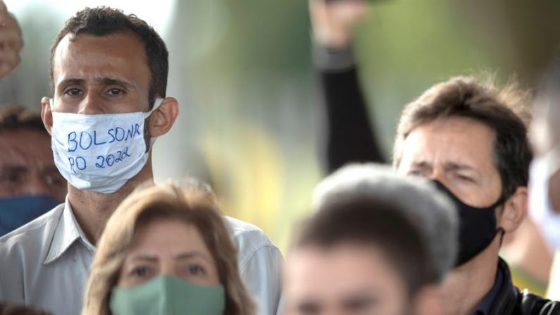 AME9478. (BRASIL), 13/05/2020.- Un simpatizante del presidente de Brasil, Jair Bolsonaro (fuera de cuadro), usa una mascarilla con el mensaje "Bolsonaro 2022" durante una rueda de prensa del mandatario, frente al Palácio do Alvorada, en Brasilia (Brasil). EFE/ Joédson Alves
