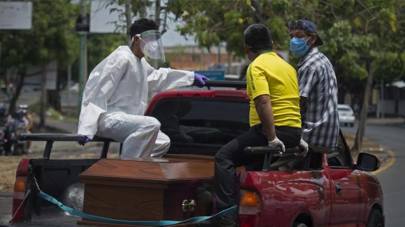 Tres personas viajan sobre una camioneta que traslada un ataúd hacia un cementerio, este jueves en Managua (Nicaragua). EFE/Jorge Torres

