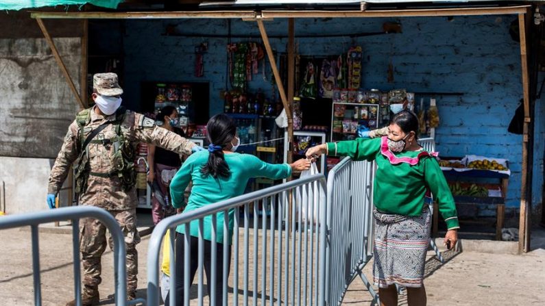 Una indígena pasa alimentos a una mujer el 13 de mayo de 2020 en Cantagallo, la comunidad indígena urbana del centro de Lima (Perú). EFE/ Sergi Rugrand
