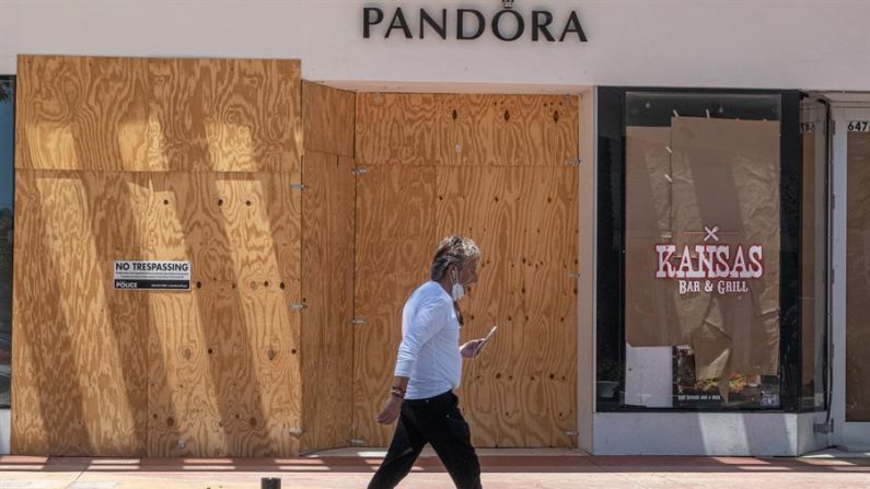 Un hombre camina ayer martes frente a la joyería Pandora cerrada por el coronavirus en la turística calle de Ocean Drive en Miami Beach, Florida (Estados Unidos). EFE/Giorgio Viera
