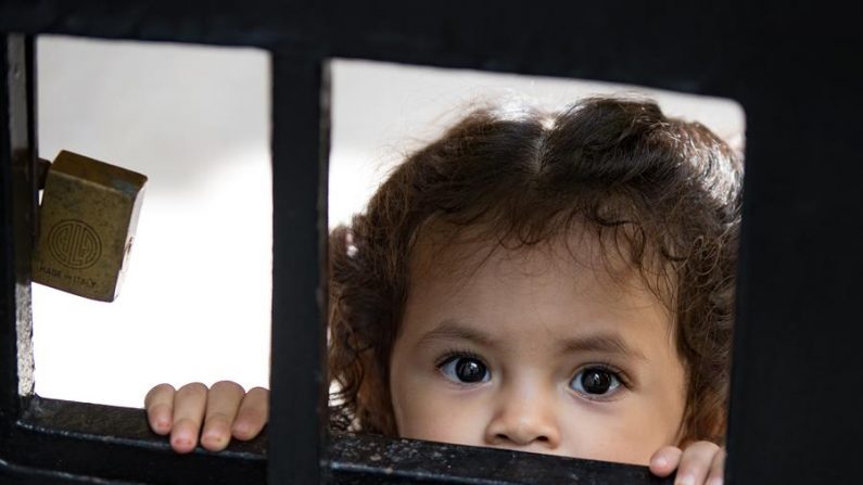 QUITO (ECUADOR) 11/05/2020. Una niña ecuatoriana mira a la calle a través de una pequeña ventana de la puerta de su casa en Quito (Ecuador).  EFE/José Jácome
