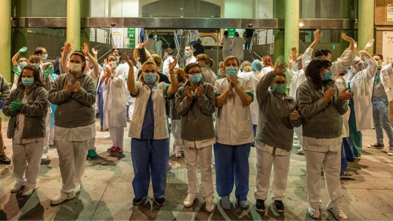 Los trabajadores de la salud aplauden a los ciudadanos que sostienen un flash mob desde sus balcones para agradecer a los trabajadores de la salud que tratan a los pacientes de coronavirus, fuera del Hospital Clínico el 26 de marzo de 2020 en Barcelona, España. (David Ramos/Getty Images)