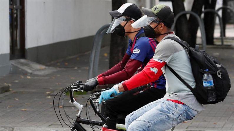 Personas con mascarillas y caretas protectoras se movilizan en bicicleta el 11 de marzo de 2020 por las calles de Bogotá (Colombia). EFE/ Carlos Ortega
