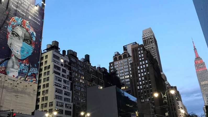 Foto de archivo de la Ciudad de Nueva York. Unas personas caminan frente a un edificio (i) con un mural del artista Tristan Eaton dedicado "En honor a las valientes enfermeras. Ahora y siempre"el mural y el Empire State (d) este martes en el centro de Nueva York. (EFE/Nora Quintanilla)
