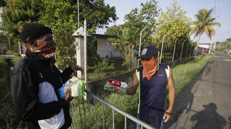 Dos indígenas Gunas intercambian alimento en el marco de la cuarentena en Koskuna, Veracruz (Panamá). EFE/Carlos Lemos/Archivo
