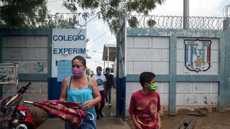 Una mujer junto a su hijo (d) utilizan tapabocas al salir de una escuela pública este viernes, en Managua (Nicaragua). EFE/ Jorge Torres
