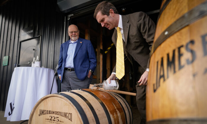 El gobernador de Kentucky Andy Beshear (Der.) llena el 16 millonésimo barril de bourbon de la destilería Jim Beam, mientras el maestro destilador Fred Noe lo observa, en la destilería Jim Beam en Clermont, Kentucky, el 17 de febrero de 2020. (Bryan Woolston/Getty Images)
