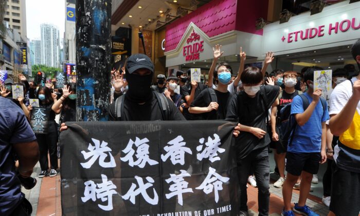 Un manifestante sostiene una pancarta con las palabras "Liberar a Hong Kong, revolución de nuestro tiempo" en una protesta en Causeway Bay, Hong Kong, el 24 de mayo de 2020. (Song Bilung/La Gran Época)
 
