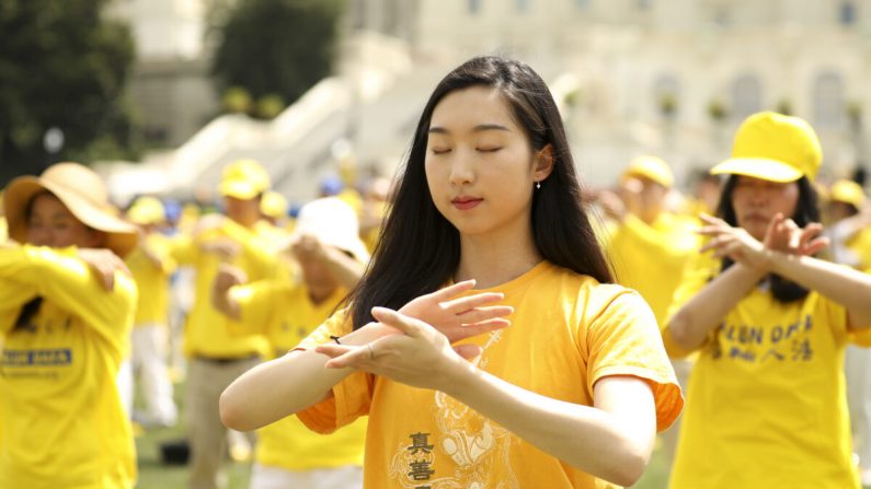 Los practicantes de Falun Dafa realizan los ejercicios en un mitin para conmemorar el 20º aniversario de la persecución a Falun Dafa en China, en el West Lawn de Capitol Hill el 18 de julio de 2019. (Samira Bouaou/The Epoch Times)