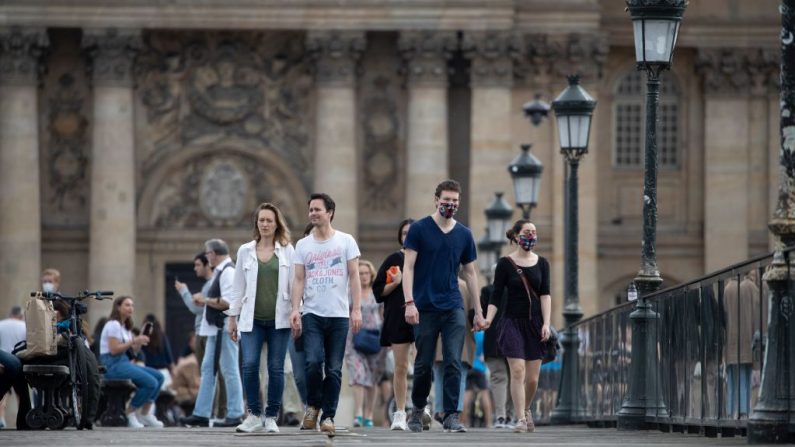 Gente, algunos con una máscara facial protectora, caminan por el Pont des Arts, sobre el río Sena en París, el 9 de mayo de 2020, en el 54º día de un encierro en Francia para frenar la propagación de COVID-19, causado por el virus del PCCh. (THOMAS SAMSON/AFP vía Getty Images)