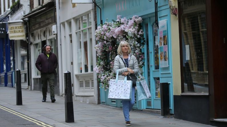 La gente camina a lo largo de una calle pasando tiendas cerradas debido al virus del PCCh, en Londres, Inglaterra, el 13 de mayo de 2020, cuando la gente empieza a volver al trabajo después de que las restricciones del cierre de COVID-19 se hayan suavizado. (ISABEL INFANTES/AFP vía Getty Images)