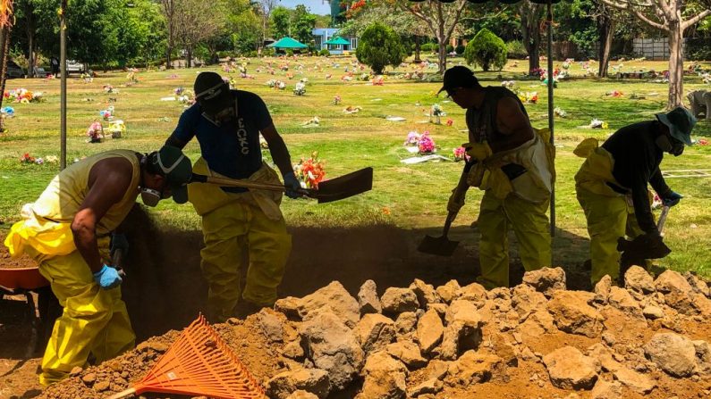 Los sepultureros, que usan trajes y máscaras para prevenir la propagación del COVID-19, entierran a una persona muerta en el Cementerio "Jardínes del Recuerdo", en Managua (Nicaragua), el 15 de mayo de 2020. (INTI OCON/AFP vía Getty Images)