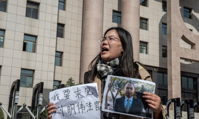 Xu Yan, esposa del abogado de derechos humanos Yu Wensheng, sostiene un trozo de papel en el que se lee "Quiero solicitar una reunión con el Juez Liu Mingwei" y una foto de su esposo frente al Tribunal Popular Intermedio de Xuzhou, en Xuzhou (China), el 31 de octubre de 2019. (Nicolas Asfouri/AFP vía Getty Images)