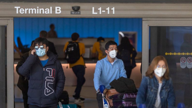 Los viajeros llegan a la Terminal Internacional Tom Bradley de LAX con máscarillas médicas para protegerse contra el nuevo brote de coronavirus en Los Ángeles, California, el 2 de febrero de 2020. (David McNew / Getty Images)
