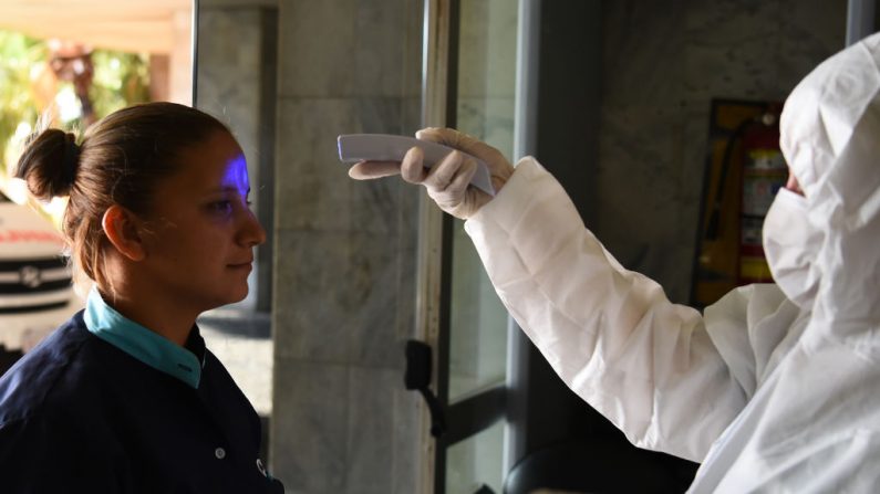 Un trabajador de la salud revisa la temperatura a los que entran al Palacio de Justicia, como parte de las medidas preventivas del gobierno para mitigar la propagación del Coronavirus COVID-19, en Asunción, el 13 de marzo de 2020. (Foto de NORBERTO DUARTE/AFP vía Getty Images)
