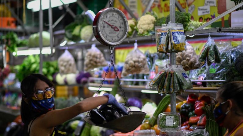 Una mujer con una máscara facial como medida preventiva contra la propagación del COVID-19, compra comestibles en un mercado municipal de Caracas (Venezuela), el 20 de marzo de 2020. (FEDERICO PARRA/AFP vía Getty Images)