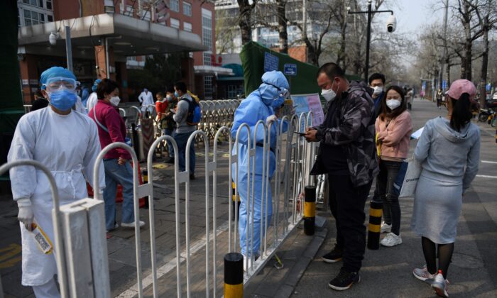 El personal del hospital (iz) registra a los pacientes en la acera de las afueras de un hospital infantil en Beijing, China, el 31 de marzo de 2020. (GREG BAKER/AFP vía Getty Images)