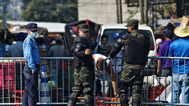 Soldados y un policía con máscara facial contra la propagación del virus del PCCh bloquean una calle de Tegucigalpa (Honduras) el 8 de abril de 2020. (ORLANDO SIERRA/AFP vía Getty Images)