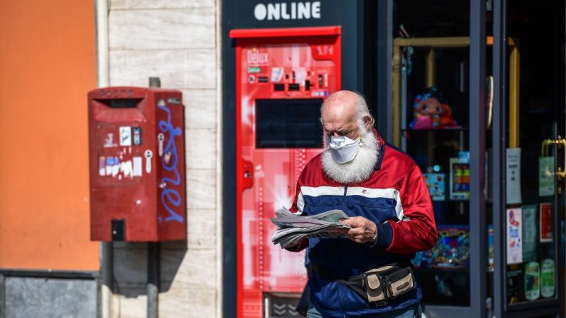 Un residente usa una máscara protectora al salir de una tienda después de comprar un periódico en Treviolo, Italia, el 9 de abril de 2020. (Miguel Medina/AFP vía Getty Images)